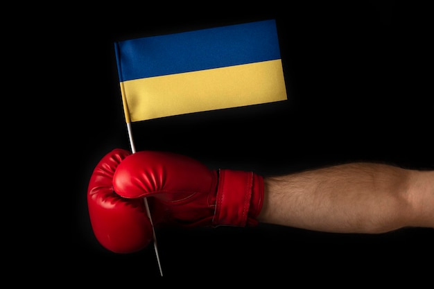 La main du boxeur tient le drapeau de l'Ukraine Gant de boxe avec le drapeau de l'Ukraine Fond noir