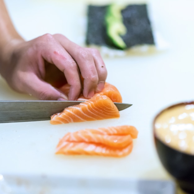 Main du chef faisant du sushi au saumon