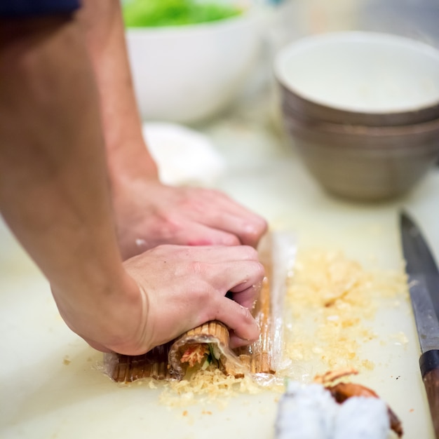 Main du chef faisant des rouleaux de sushi