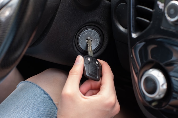 Photo la main du conducteur, en insérant une clé de voiture, allumez le moteur de la voiture, prêt pour le voyage.