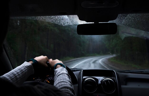 La main du conducteur sur un volant à l'intérieur d'une voiture sur une route