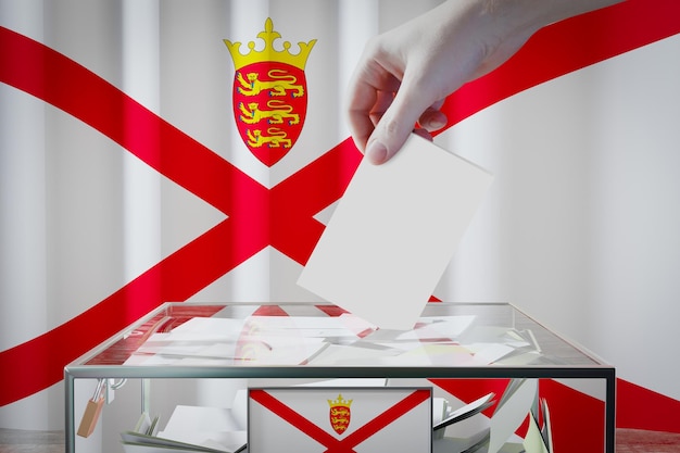 Main du drapeau de Jersey laissant tomber le bulletin de vote dans un concept d'élection de vote de boîte