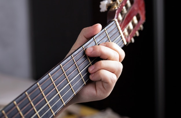 La main du guitariste serre les doigts sur les accords d'une guitare acoustique.