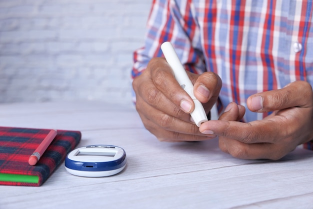 Photo la main du jeune homme mesure le niveau de glucose à la maison