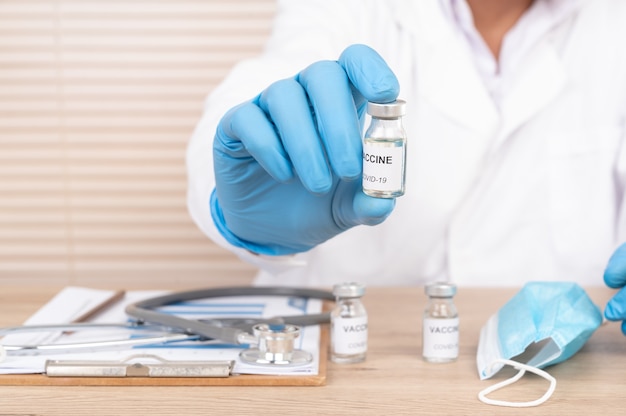 La main du médecin tenant le flacon de vaccin sur le bureau du médecin