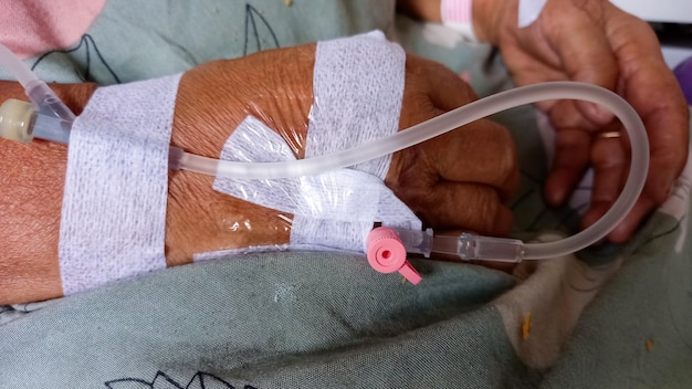 La main du patient est au goutte-à-goutte recevant une solution saline sur le lit dans la salle VIP de l'hôpital