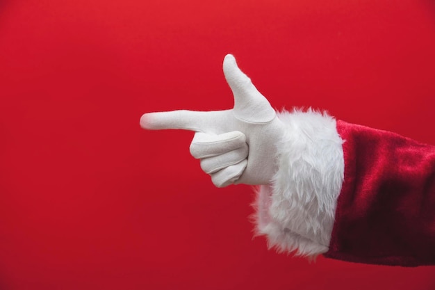 Main du Père Noël pointant du doigt sur un fond rouge