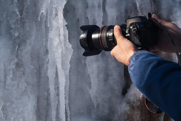 La main du photographe avec un appareil photo reflex numérique moderne tire