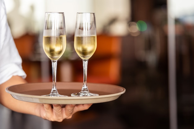 La main du serveur apporte des verres de champagne sur un plateau.