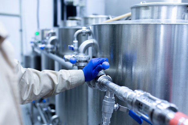 La main du travailleur tournant la vanne d'eau d'une canalisation sur l'usine