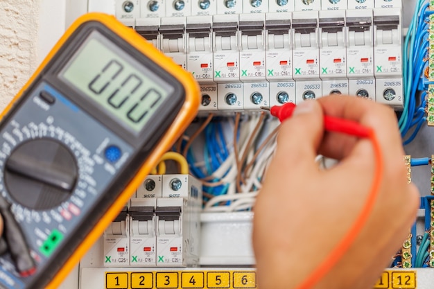 Photo main d'un électricien avec sonde multimètre à un électrique