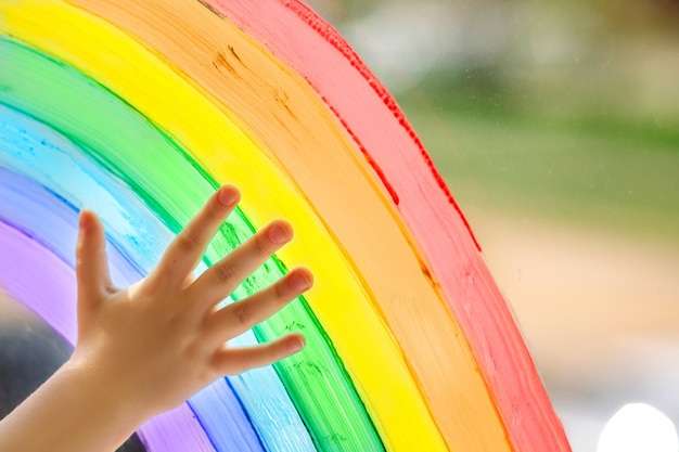 La main d'un enfant sur un arc-en-ciel peint.