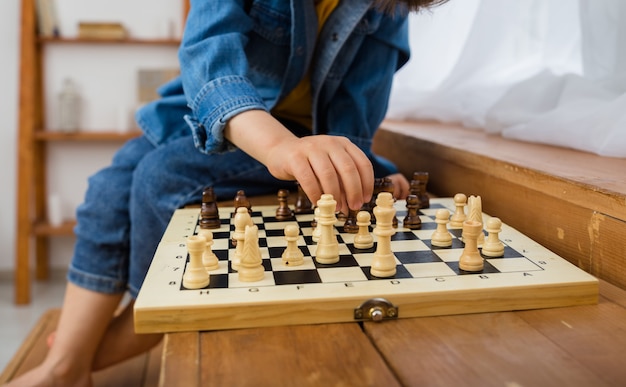 La main de l'enfant joue aux échecs sur l'échiquier dans la salle