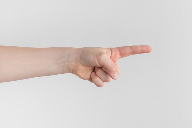 Photo la main de l'enfant pointant l'index vers la droite au-dessus d'un fond de papier blanc