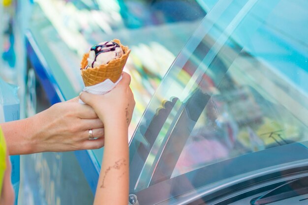 La main de l'enfant prend la corne avec de la glace