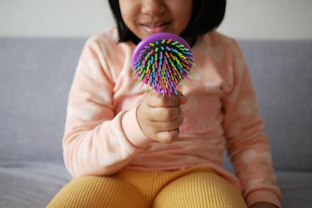 main d'enfant tenant une brosse à cheveux colorée à la maison