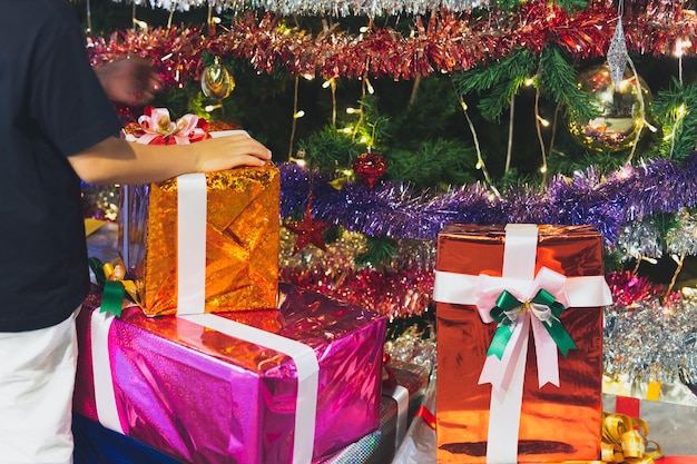 Main d'enfants sur des cadeaux de Noël et des coffrets cadeaux sous le sapin de Noël