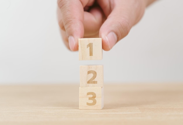 Main d'entreprise organisant l'empilement de cubes de bois comme escalier. Processus de réussite de croissance de concept d'entreprise sur fond blanc, espace de copie.