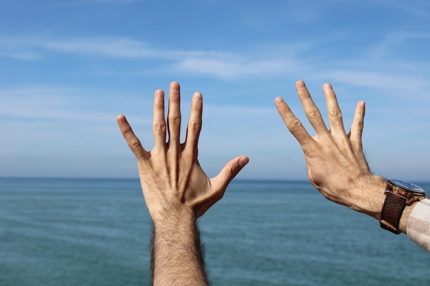 Main faisant montrant le symbole de geste numéro neuf sur fond bleu ciel d'été nature numéro 9