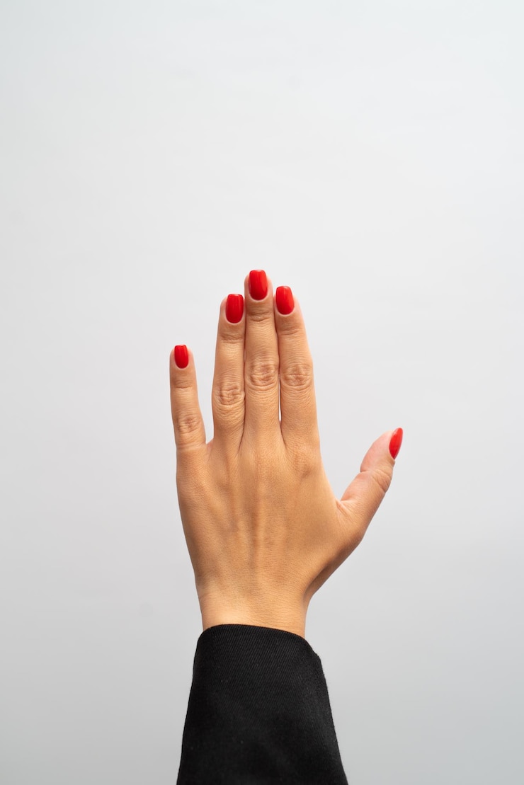Photo la main femelle avec la manucure rouge montre le geste sur le fond blanc