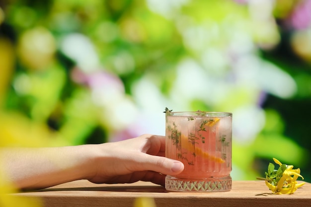 La main femelle tient le verre du cocktail de pamplemousse d'été