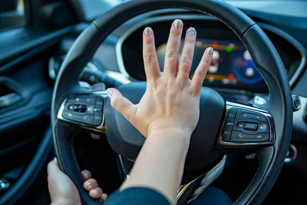 Photo la main féminine appuie sur le klaxon sur le volant d'une voiture moderne. pas de visage