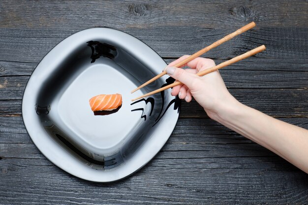 Main féminine avec des baguettes et des sushis. Vue de dessus