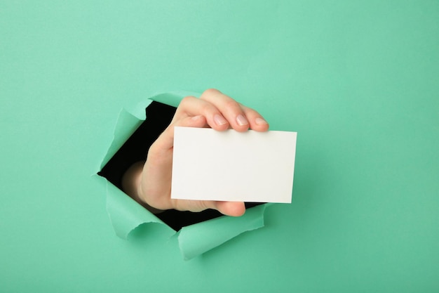 Main féminine avec boîte-cadeau perforant le papier rose Vue de dessus