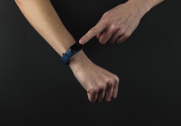 Main féminine avec un bracelet intelligent sur fond noir. Gadgets modernes