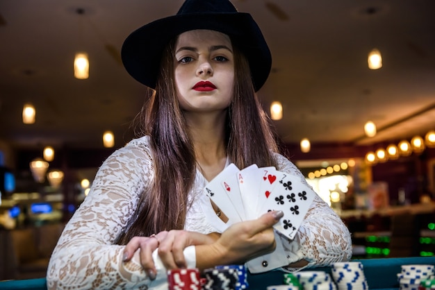 Main féminine avec des cartes à jouer et des jetons de poker se bouchent