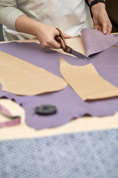 Main féminine avec les ciseaux coupant le tissu