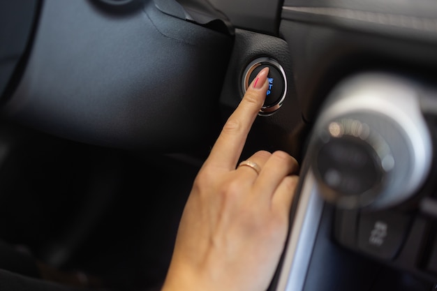 Main féminine avec clé de démarrage à l'intérieur de la voiture.