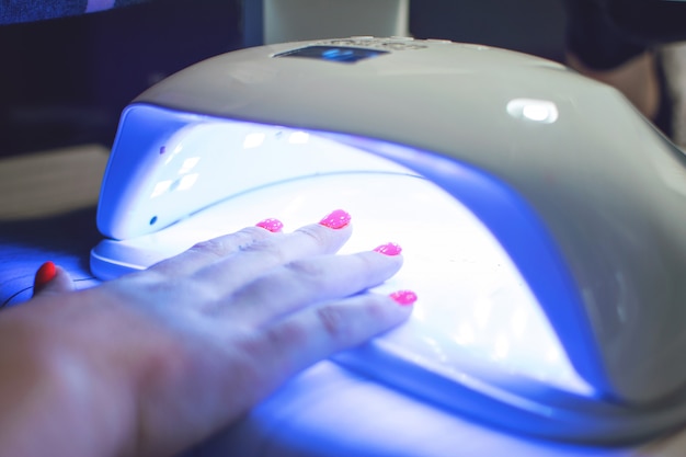 Main féminine avec des clous rouges dans une lampe à LED