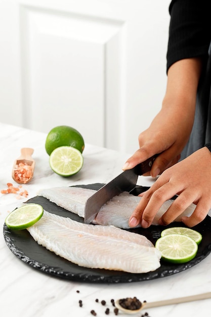 Photo main féminine coupant le filet de dori au-dessus de la planche de pierre