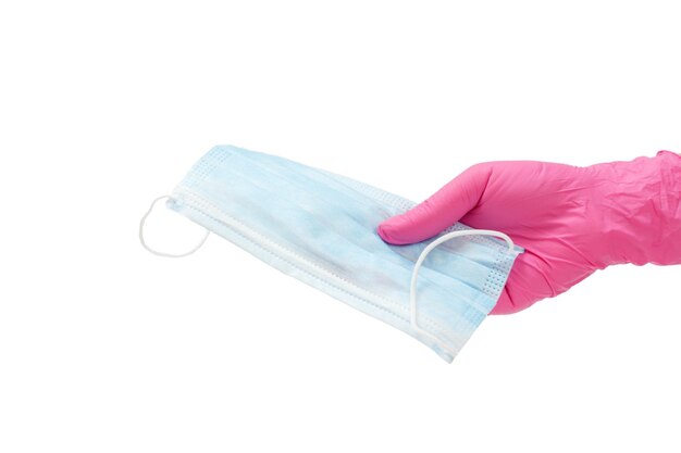 Main féminine dans un gant en latex rose tenant un masque de protection médicale sur un fond blanc isolé