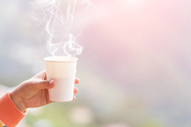 Main féminine dans des mitaines tenant une tasse de thé ou de café chaud. Pause thé