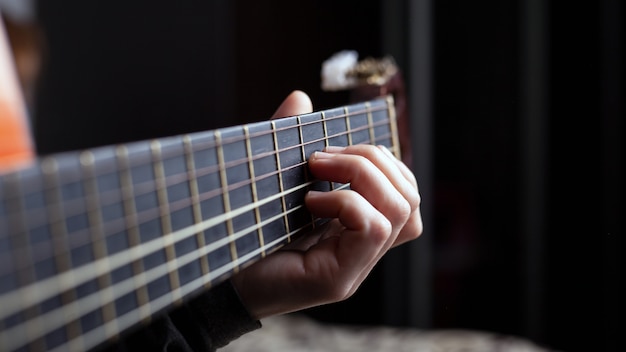 Main féminine détient un accord sur une guitare acoustique.