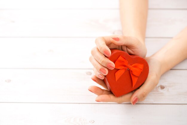 Main féminine donnant tenant une boîte en forme de coeur