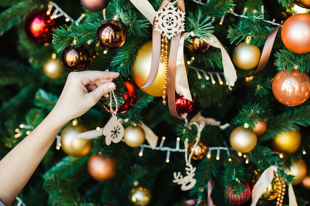 Une main féminine est suspendue au jouet en bois de sapin de Noël sous la forme de mitaines.