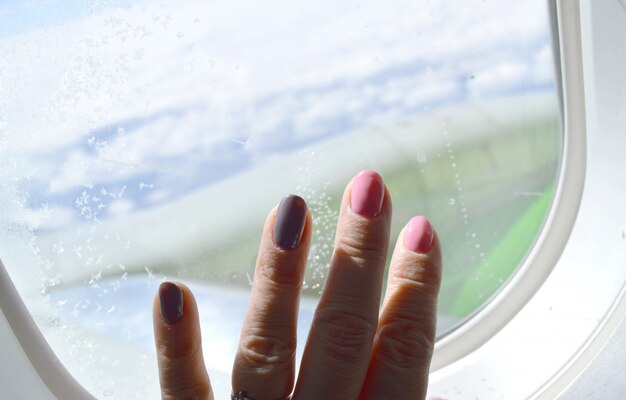 Main féminine sur le fond de la fenêtre dans l&#39;avion.