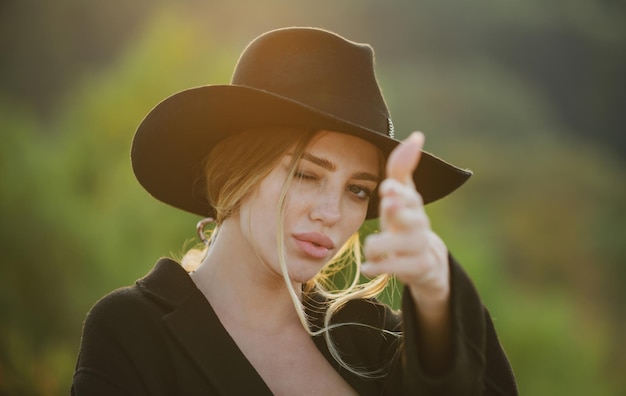 Main féminine en geste de pistolet portrait d'une jeune femme bouchent le visage d'une belle femme en plein air cheerf