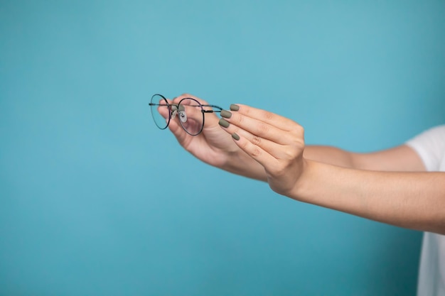 Main féminine avec des lunettes élégantes sur fond coloré