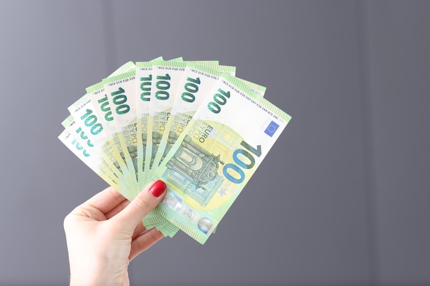 Main féminine avec manucure rouge tenant beaucoup de billets en euros en gros plan gagnant à la loterie