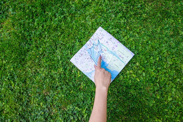 Une Main Féminine Montre Un Doigt Sur Une Carte Topographique Sur L'herbe