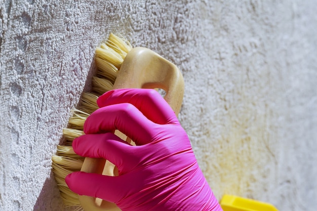 La main féminine nettoie le tapis avec une brosse et un détergent