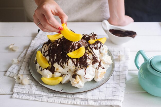 La main féminine pose des tranches de pêche sur un gâteau sancho pancho cuisine maison réconfortante nourriture calorique