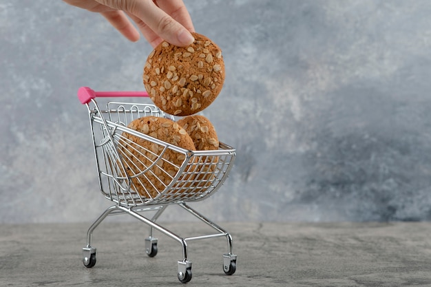 Main féminine prenant des biscuits à l'avoine avec des graines sur la pierre.