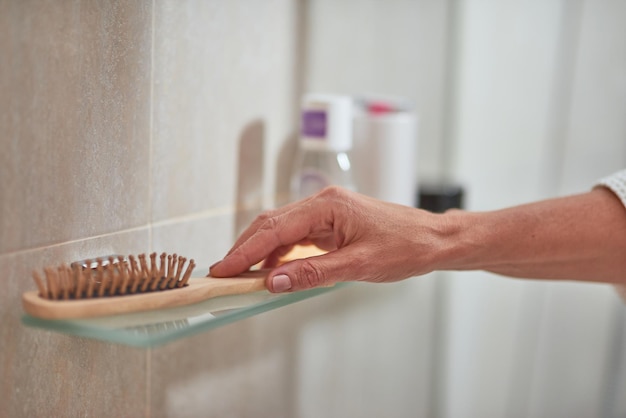 Main féminine prenant une brosse à cheveux en bois