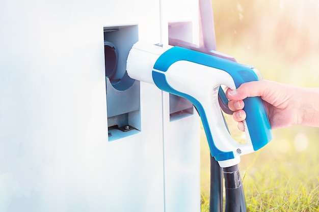 Main féminine prenant en charge les voitures électriques à l'extérieur. Respectueux de la nature