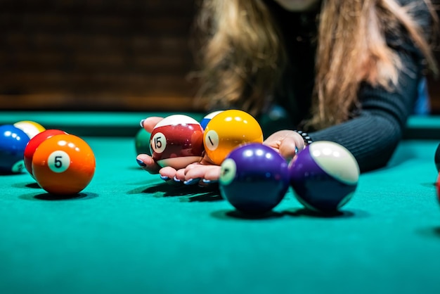 La main féminine recueille des balles colorées après avoir joué au billard et prépare un nouveau jeu